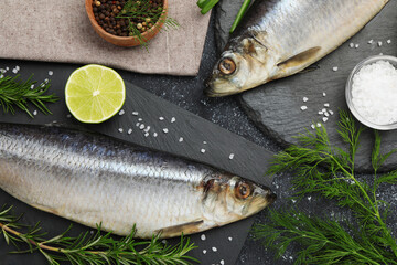 Delicious salted herrings and ingredients on dark grey table, flat lay