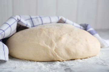 Fresh yeast dough with flour on white marble table, closeup