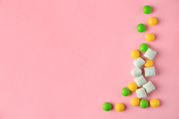 Different tasty chewing gums on pink background, flat lay. Space for text