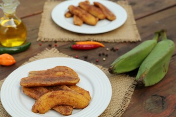 Delicious fried bananas, fresh fruits and different peppers on wooden table
