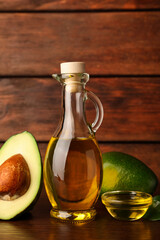 Cooking oil and fresh ripe avocados on wooden table