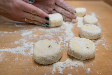 close up of female hand forms a dumpling of cottage cheese dough on a cutting board