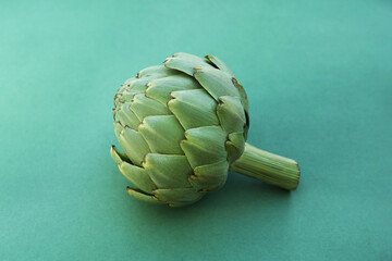 Whole fresh raw artichoke on green background. closeup