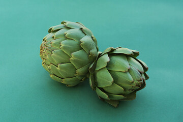 Obraz premium Whole fresh raw artichokes on green background, closeup