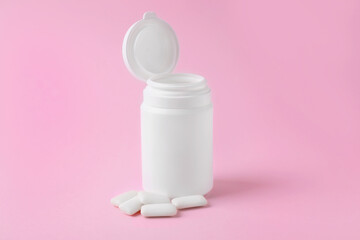 Jar with chewing gums on pink background