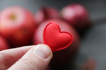 Obraz premium Healthy food concept. Hand holding a heart on the background of an apple.