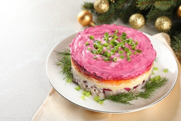 Herring under fur coat salad and Christmas decor on light grey table, space for text. Traditional Russian dish
