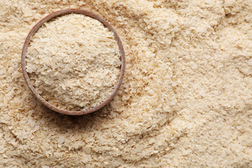 Wooden bowl of brewer`s yeast on flakes, top view