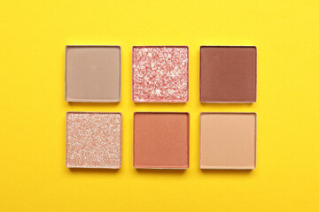 Beautiful eye shadow refill pans on yellow background, flat lay