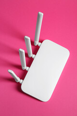 New white Wi-Fi router on pink background, top view