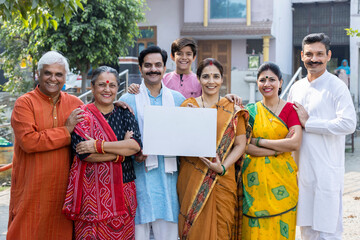 Portrait of happy multi-generation family standing at outside the home and showing white sheet.