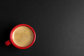 Red ceramic cup with hot aromatic coffee on black background, top view. Space for text