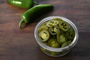 Fresh and pickled green jalapeno peppers on wooden table, closeup. Space for text