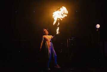 Fire show, dancing with flame, master with fireworks, performance indoors, draws a fiery figure in...