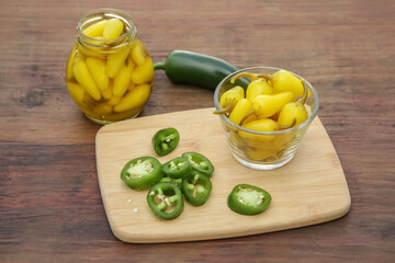 Fresh and pickled jalapeno peppers on wooden table