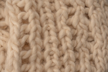 A fragment of beige knitted fabric, knitted from white sheep wool.