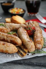 Tasty fresh grilled sausages with vegetables on grey table, closeup