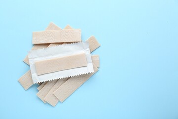 Many sticks of tasty chewing gum on light blue background, flat lay. Space for text