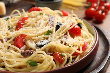Delicious pasta with anchovies, tomatoes and parmesan cheese on table, closeup