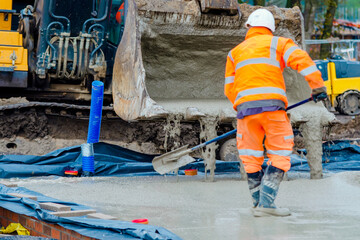 Builder pouring ground floor slab of a new house with wet ready-mix concrete, levelling it and...
