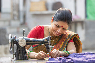 Fototapeta na wymiar Indian rural woman using sewing machine at home