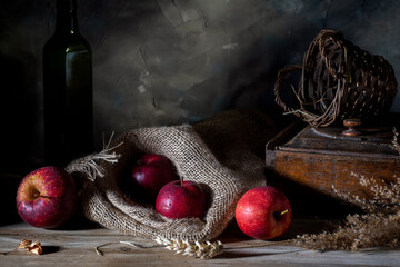Red apples and a wicker basket on a rustic table