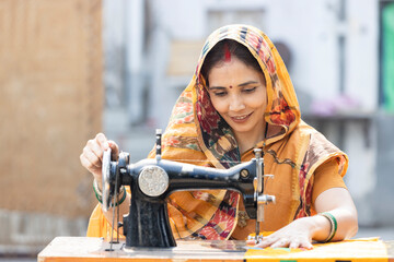 Indian rural woman using sewing machine at home