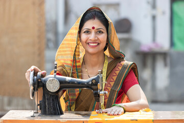 Indian rural woman using sewing machine at home