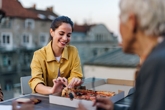 Smiling Woman Taking A Pizza Slice, Taking A Lunch Break With Colleague.