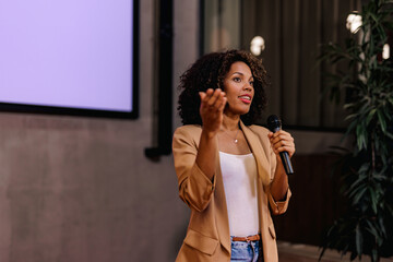 African businesswoman giving a speech, standing in the conference hall.