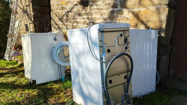 Dump of non-working washing machines. Several broken washing machines near the house. Repair concept.