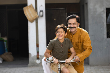 Rural father and son riding bicycle together