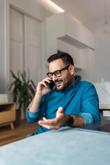 Smiling businessman having a phone call with a client, sitting at the home office.