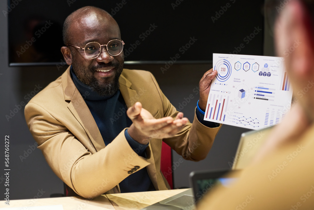 Aufkleber young confident analyst with financial paper document looking at colleague while explaining graphic 