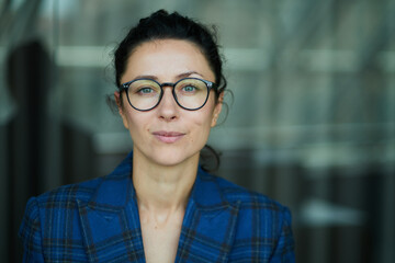 Portrait of a business woman with glasses smiling and happy. Dark blue jacket, confident woman looking in the camera High quality photo