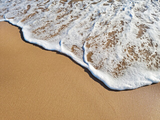 Ocean foam covering beautiful sandy beach. Top view.