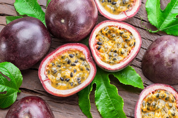 Dark purple passion fruits and it's half with seedly interior on wooden table.
