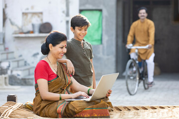 Rural Indian parents with son using laptop at village