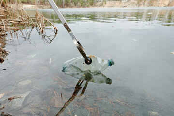 Volunteer picking plastic bottles from lake, beach clean up day
