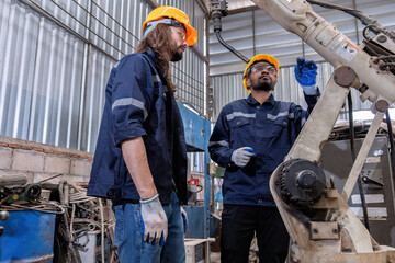 Factory maintenance engineer working with old defected robotic arm in maintenance workshop