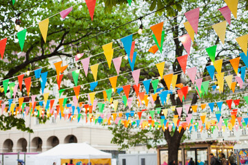 Fototapeta na wymiar Easter market with colorful flags bunting banner and lights decoration. Festive happy birthday celebration background.