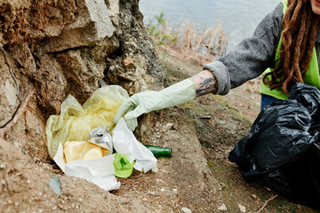 Cropped image of young woman wearing gloves when picking up trash left by tourists