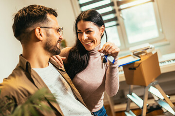 Smiling couple unpacking boxes in new home.New life.They are showing key of their new house.