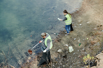 Young people picking up garbage on lakeshore, view from above