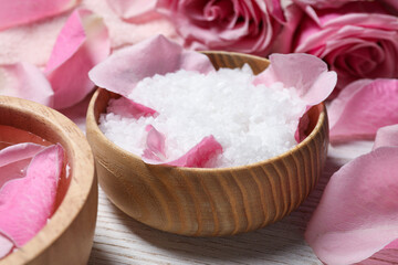 Naklejka na ściany i meble Bowl with sea salt and beautiful petals of roses on white wooden table, closeup