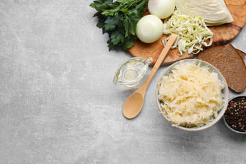 Bowl of tasty sauerkraut and ingredients on grey table, flat lay. Space for text