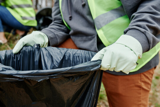 Closeup image of volunteer holding big trash bag for garbage collected in city park