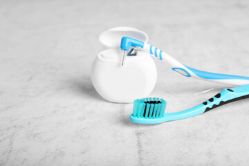 Container with dental floss and toothbrushes on light grey textured table