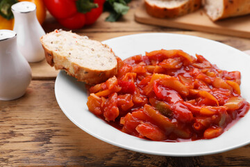 Delicious lecho with bread on wooden table, closeup