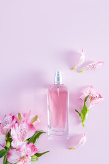 Obraz na płótnie Canvas vertical view of the bottle with a spring floral fragrance of women's perfume. delicate pink flowers and buds. lilac background. a copy space.
